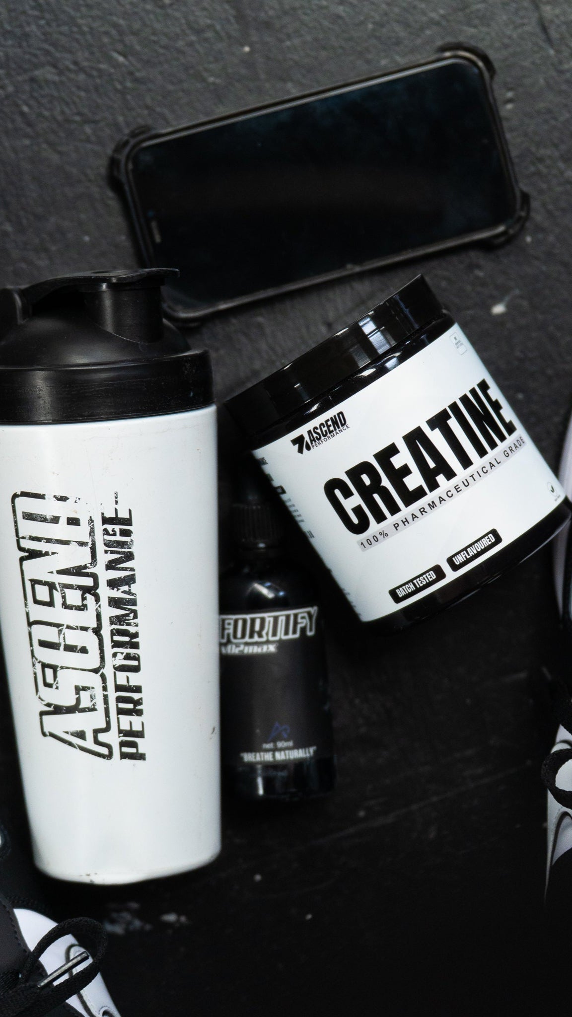 Supplement containers including a shaker and a creatine container on a dark surface.